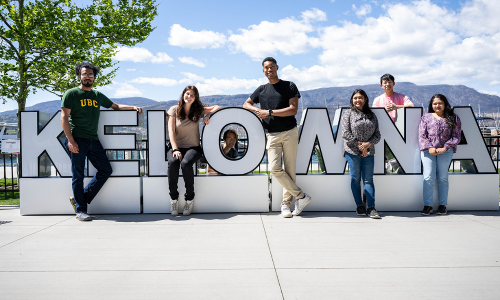 Students standing around Kelowna sign in downtown Kelowna